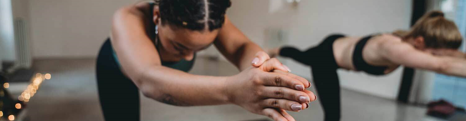 Girl in green workout attire doing yoga pose infront of yellow backdrop