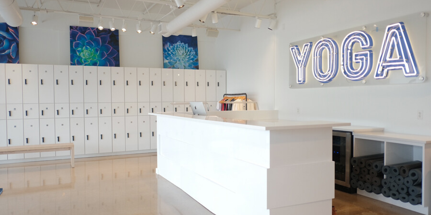 Yoga studio with lockers, a front desk, and a blue yoga sign